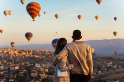 Casal de costas em lua de mel na Capadócia, Turquia, a observar paisagem com balões de ar quente